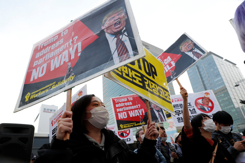 Protesters against U.S. President Donald Trump hold placards while waiting for Trump's motorcade to pass by in central Seoul, South Korea, Nov. 7, 2017.