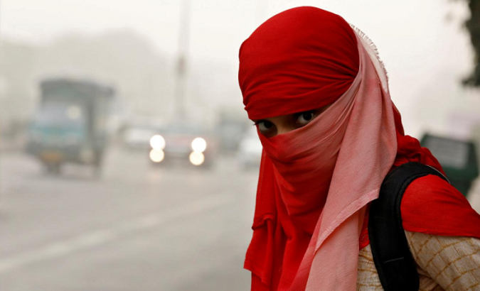 A woman wearing a scarf to cover her face on a smoggy morning in New Delhi.