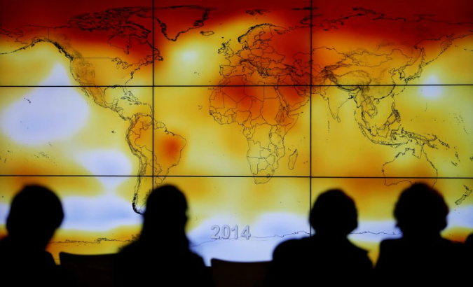 Participants are seen in silhouette as they look at a screen showing a world map with climate anomalies during the World Climate Change Conference 2015 (COP21) at Le Bourget, near Paris, France, Dec. 8, 2015.