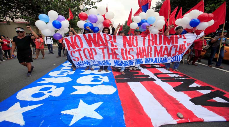 Los manifestantes portaron una gran bandera estadounidense donde escribieron consignas en contra de la cumbre y del presidente estadounidense. 