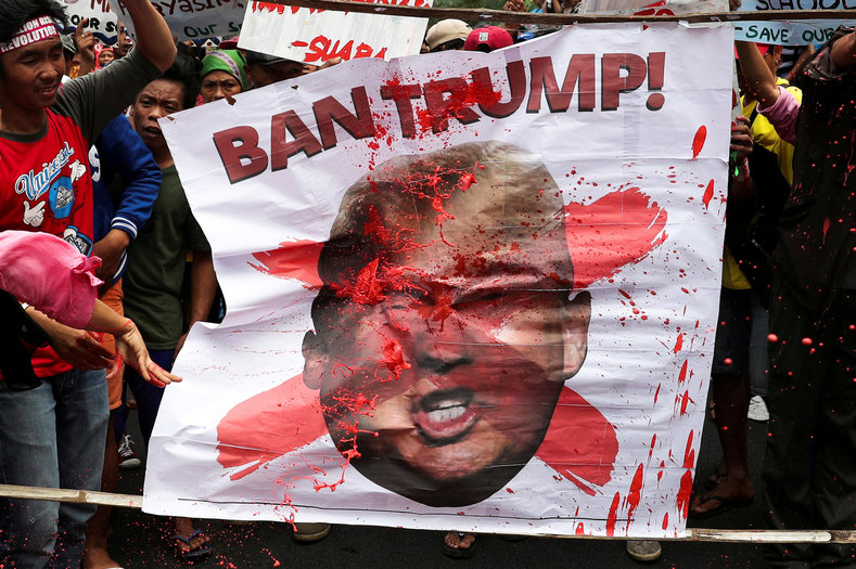 Protesters throw red paint to a picture of U.S. President Donald Trump during a rally against his visit in Manila, Philippines, November 11, 2017. 