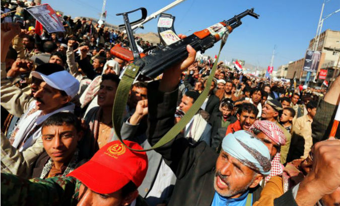 Yemenis carry signs and weapons protesting the Saudi-led war and air, land and sea blockade against the country.
