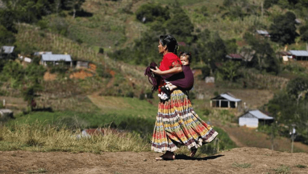 A Guatemalan Indigenous woman carries a child on her back in the village of Pumbach, 130 miles from Guatemala city 