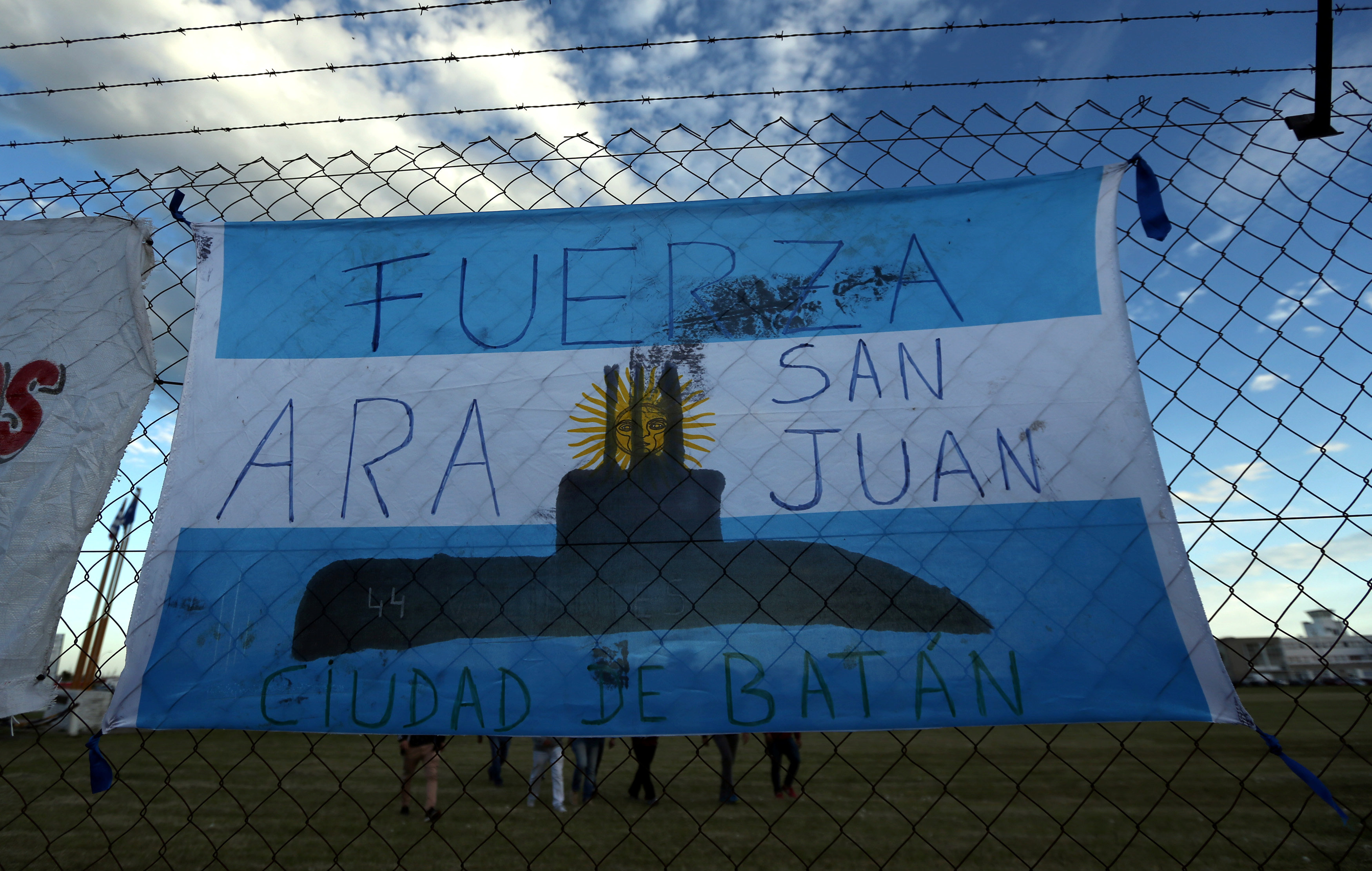 People walk behind an Argentine national flag displayed on a fence in Mar del Plata, Argentina, Nov. 22, 2017. The words on the flag read: 