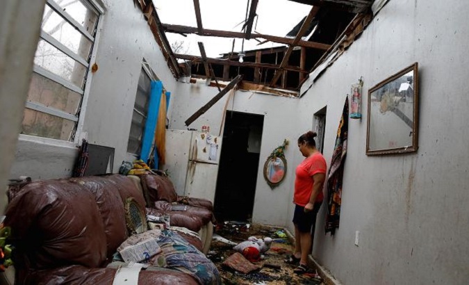 A woman stands in her home in Puerto Rico after Hurricane Maria.