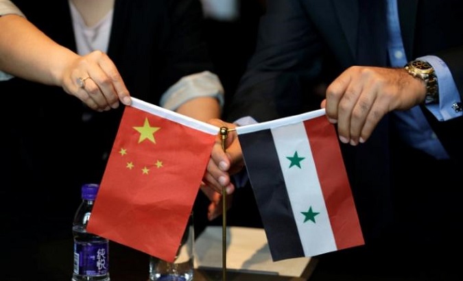 Chinese and Syrian businessmen shake hands behind their national flags during a meeting to discuss reconstruction projects in Syria, Beijing, China May 8, 2017.