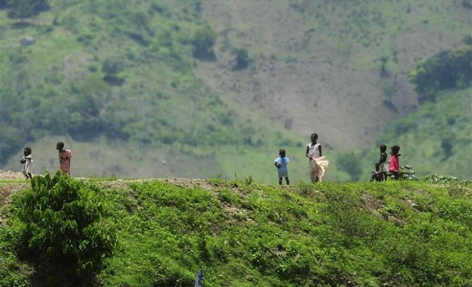 Haitian children stand on a ridge alongside the road that divides Hispaniola island into the Dominican Republic and Haiti to the west.