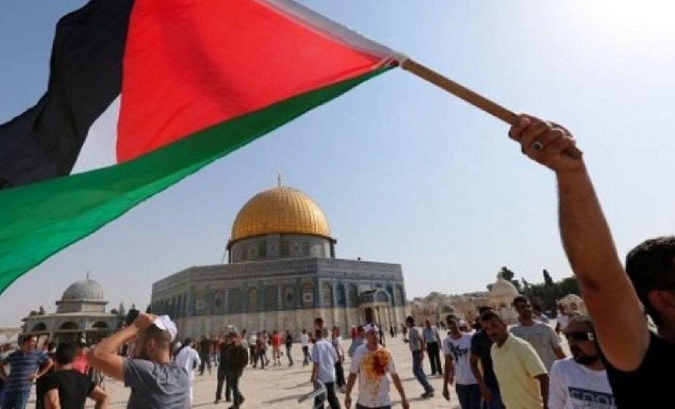 A demonstrator holds a Palestinian flag in front of the al-Aqsa Mosque.