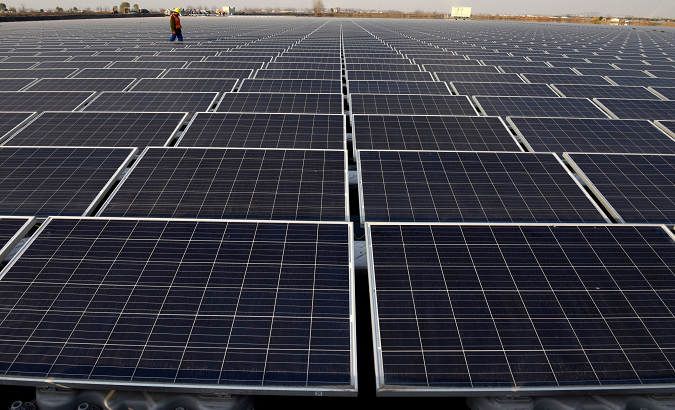 A worker examines a vast field of solar panels in China, in a scene that may some day be extended across Cuba.