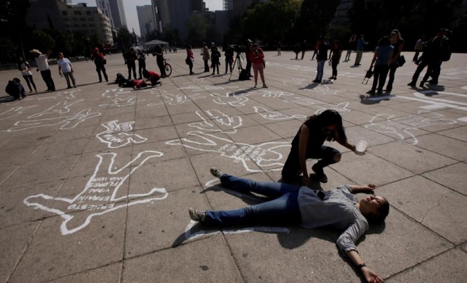 Demonstrators lie on silhouettes that represent victims of violence in Mexico City, December 2016.