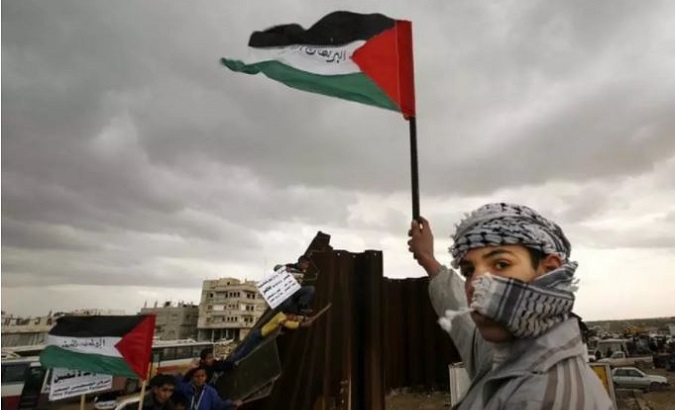 A Palestinian waves a flag near a destroyed section of the border wall between the Gaza Strip and Egypt.