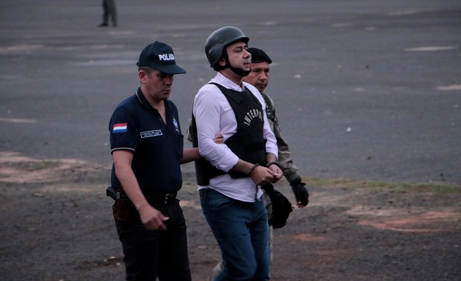 Brazil's Jarvis Chimenez Pavão (in pink shirt), is escorted by Paraguayan security forces while being extradited to Brazil.