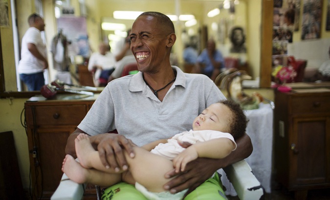 Street vendor Alain Rivera, 37, holds his 10-month-old nephew in a barber shop in downtown Havana on July 14, 2015.