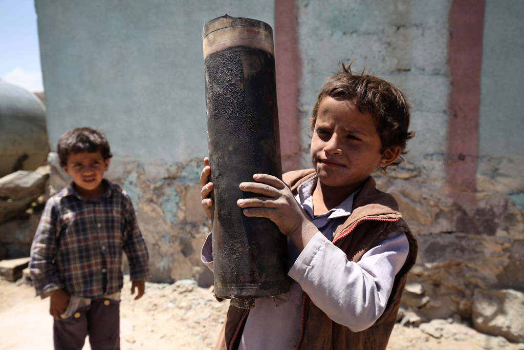 Niños yemeníes muestran un proyectil encontrado entre los escombros.