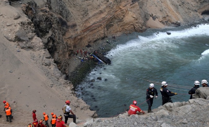 Rescue workers and police work at the scene after a bus crashed with a truck and careened off a cliff along a sharply curving highway north of Lima, Peru, January 2, 2018.