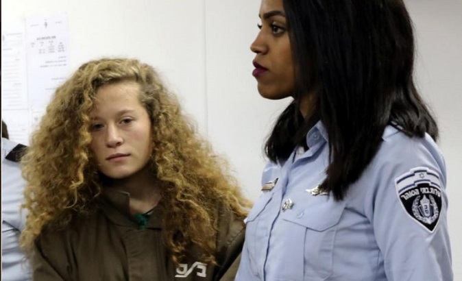 Palestinian teen Ahed Tamimi enters a military courtroom escorted by Israeli Prison Service personnel at Ofer Prison near the West Bank city of Ramallah, December 28, 2017.