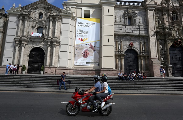 People on a motorcycle ride past Lima Cathedral with a banner of Pope Francis prior to his visit to Peru, scheduled to follow his tour of Chile.