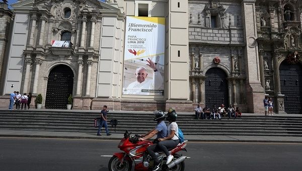 People on a motorcycle ride past Lima Cathedral with a banner of Pope Francis prior to his visit to Peru, scheduled to follow his tour of Chile. 