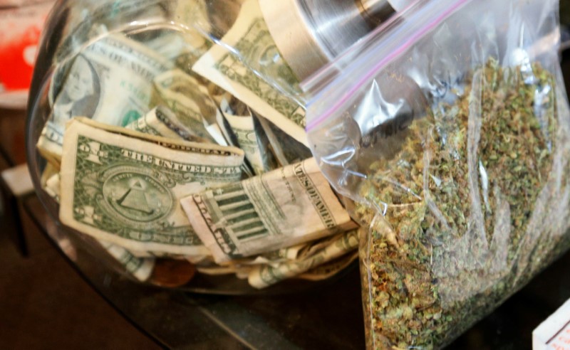 A bag of marijuana being prepared for sale sits next to a money jar at BotanaCare in Northglenn, Colorado, U.S., Dec. 31, 2013.