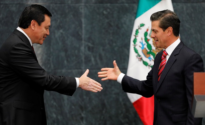 Mexican President Enrique Peña Nieto (R) and outgoing Interior Minister Miguel Angel Osorio (L) shake hands before Osorio announced his resignation.