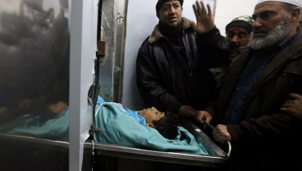 People stand next to the body of Palestinian boy Ameer Abu Mosaed, at a hospital morgue in the central Gaza Strip Jan. 11, 2018. 