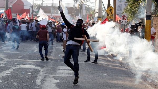 A demonstrator throws a tear-gas canister back to the police during a protest against the re-election of Honduras' President Juan Orlando Hernandez in Tegucigalpa.