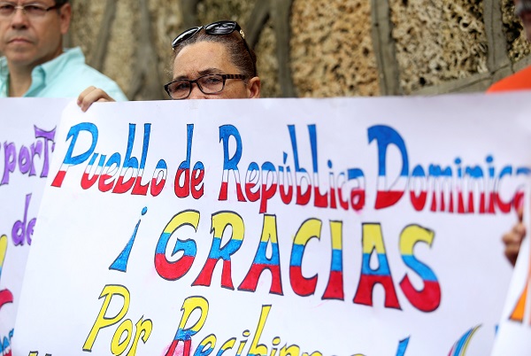Venezuelan migrants hold a sign reading 