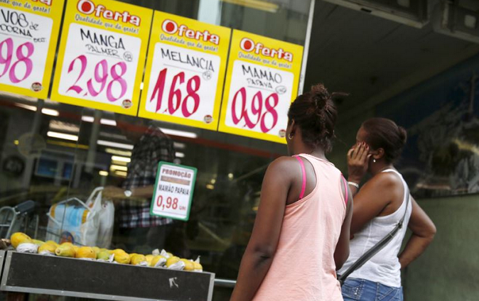 Women look at prices at a food market in Rio de Janeiro, Brazil.