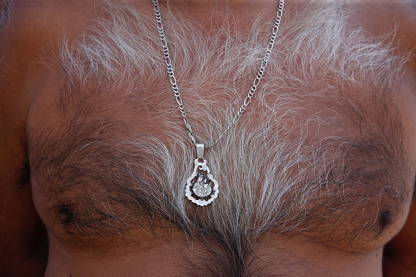 A man wears a pendant bearing the traditional 