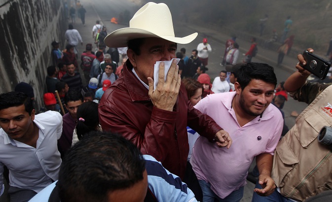 Honduras' former President Manuel Zelaya covers his mouth to protect himself from smoke during a protest against the re-election of Honduran President Juan Orlando Hernandez in Tegucigalpa, Honduras January 21, 2018