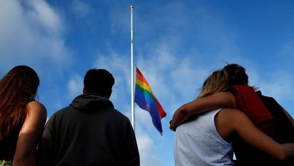 FEELING BESIEGED: Mourners in San Diego, California, gather under an LGBT pride flag at a candlelight vigil in remembrance of victims of the mass shooting in Orlando, Florida. 