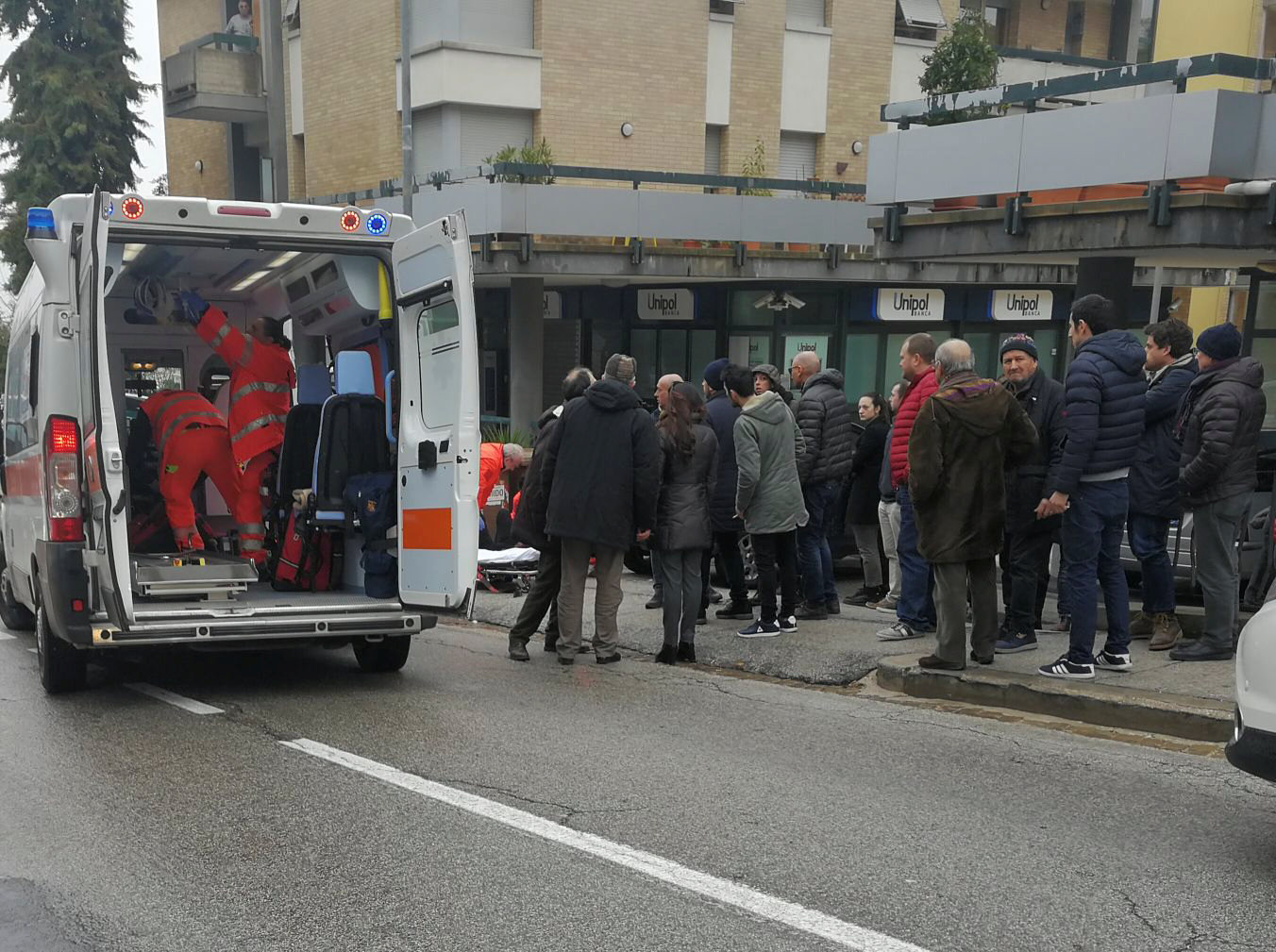 People look at healthcare personnel taking care of an injured person after being shot by gunfire from a vehicle, in Macerata, Italy, February 3, 2018.