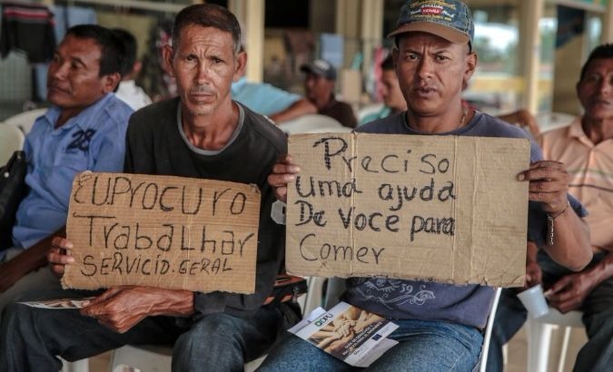Venezuelan migrants hold placards looking for work in the Brazilian city of Boa Vista.