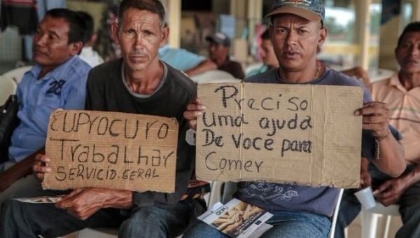Venezuelan migrants hold placards looking for work in the Brazilian city of Boa Vista.