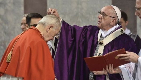 Pope Francis sprinkles ashes on a cardinal's head during the Ash Wednesday.