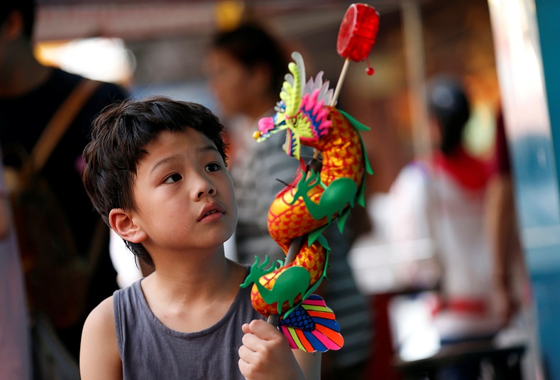 A young Thai boy plays with a dragon toy in the Chinese sector of Bangkok, Thailand.