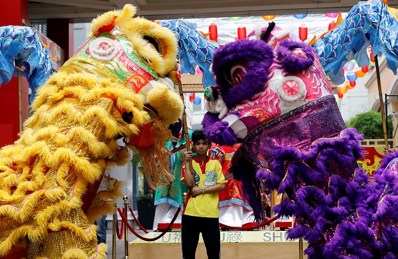 A boy stands beneath towering figures as Filipino dancers kick off the Chinese Year of the Dog celebrations in Manila.