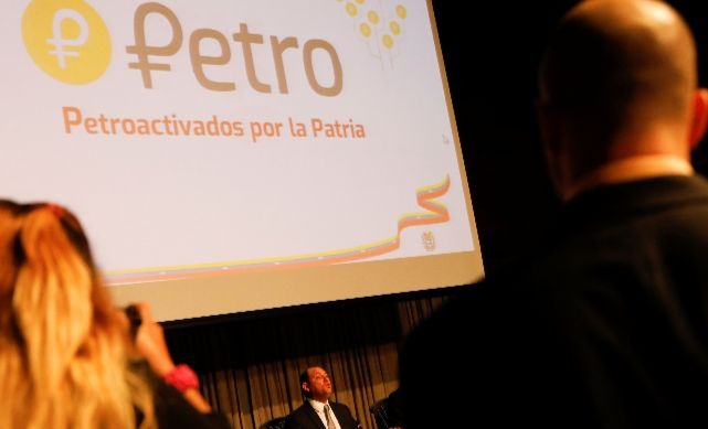 The new Venezuelan cryptocurrency the Petro logo is seen as Minister for University Education, Science and Technology Hugbel Roa talks to the media.