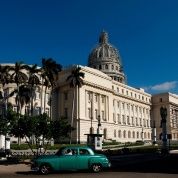 A vintage car drives in front of the Capitol building in Havana