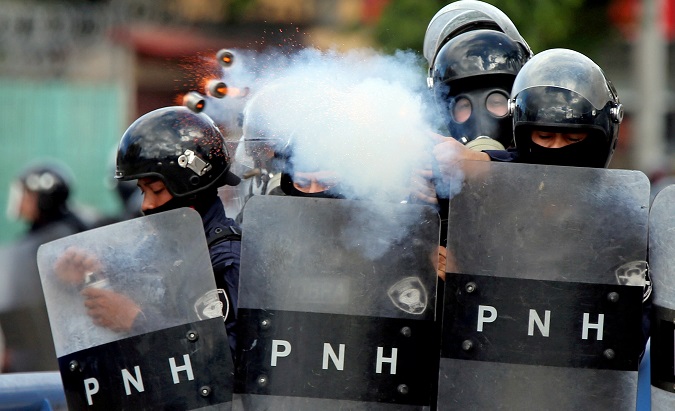 A police officer fires tear gas during clashes with demonstrators as Honduran President Juan Orlando Hernandez is sworn in for a new term in Tegucigalpa