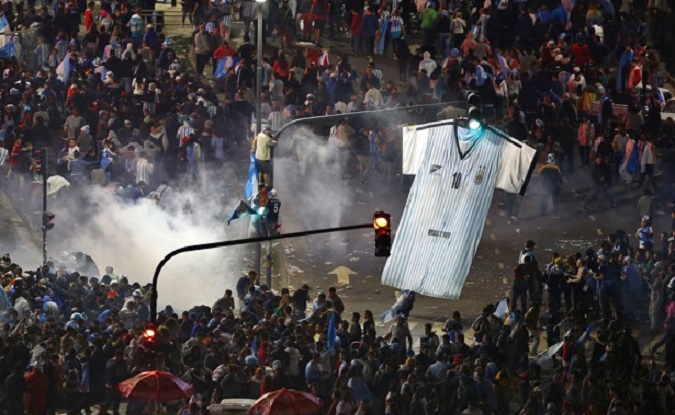 Argentina's fans run away from tear gas as they clash with riot police in Buenos Aires after Argentina's World Cup loss to Germany