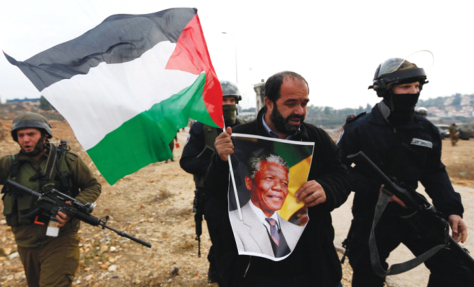 Palestinian activist holds a picture of late South African President Nelson Mandela during a protest in the West Bank.