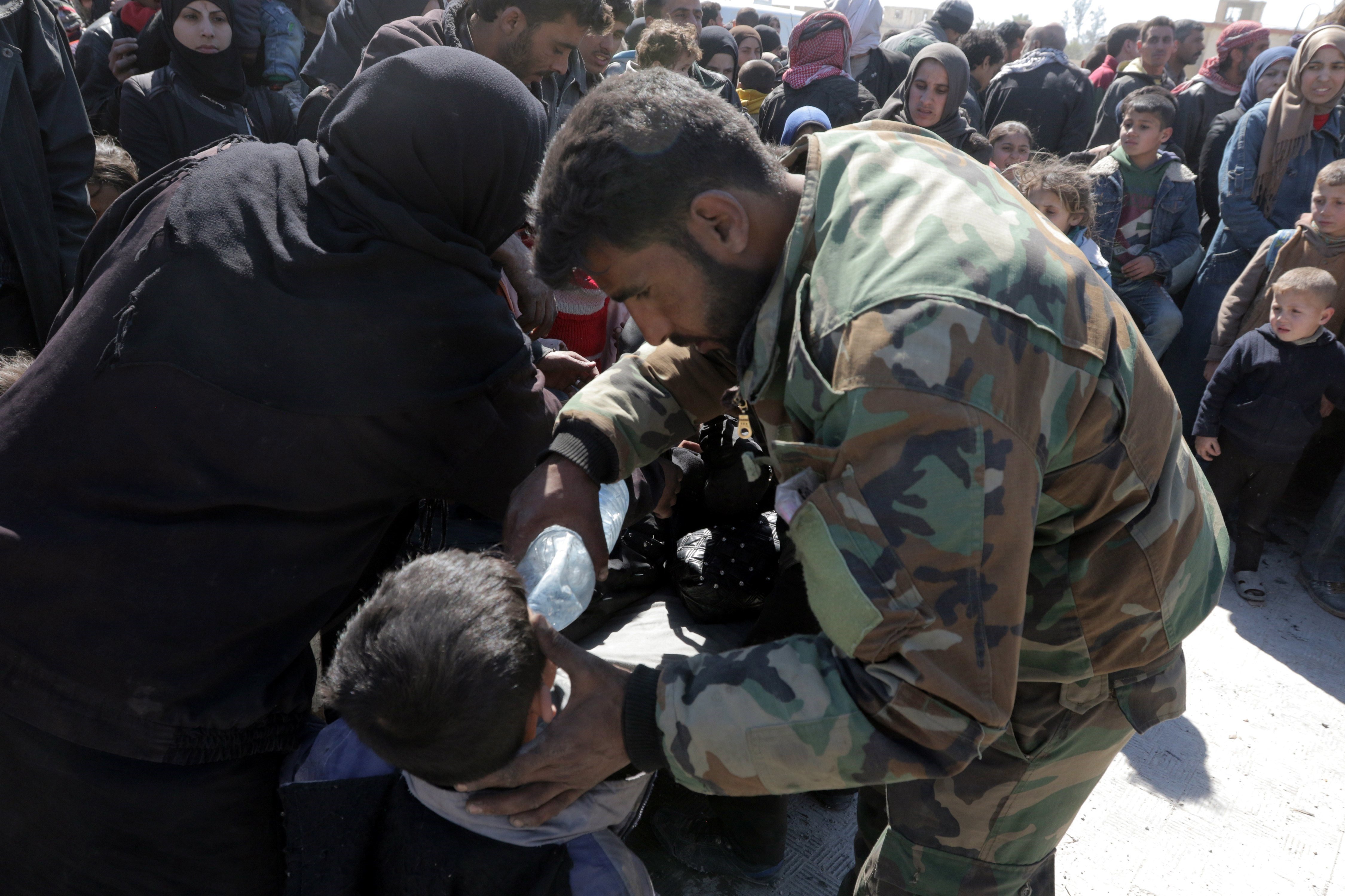 Soldados sirios ayudando a civiles en los corredores humanitarios en las afueras de Damasco.