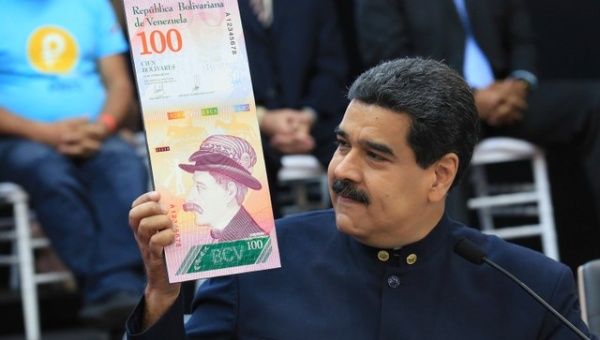 Venezuela's President Nicolas Maduro holds a sample of the new hundred bolivars notes during a meeting with the ministers responsible for the economic sector at Miraflores Palace in Caracas, Venezuela March 22, 2018.