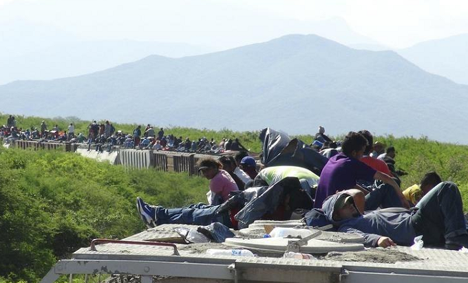 People hoping to reach the U.S. ride atop the wagon of a freight train, known as La Bestia (The Beast) in Ixtepec, in the Mexican state of Oaxaca June 18, 2014.