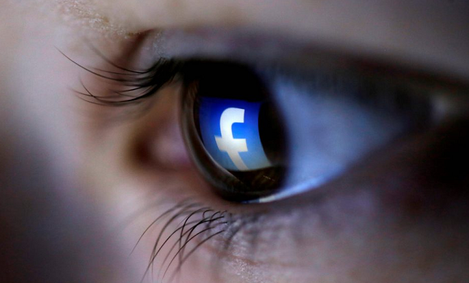 A picture illustration shows a Facebook logo reflected in a person's eye, March 13, 2015.