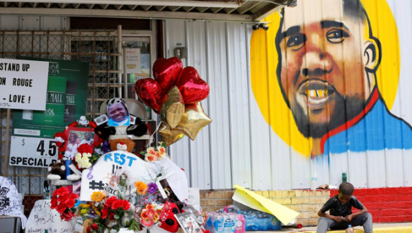 A boy sits next to a makeshift memorial outside the Triple S Food Mart where Alton Sterling was fatally shot by police in Baton Rouge, Louisiana, U.S. July 7, 2016. 