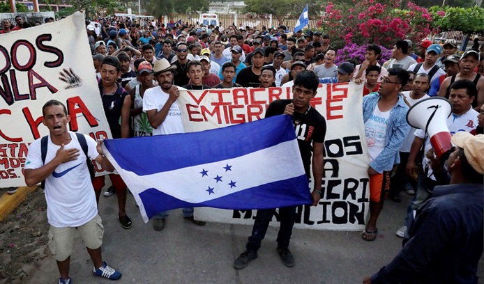 Honduran migrants hold their national flag as they take a pause from traveling in their caravan, during their journey to the U.S./Mexico border.