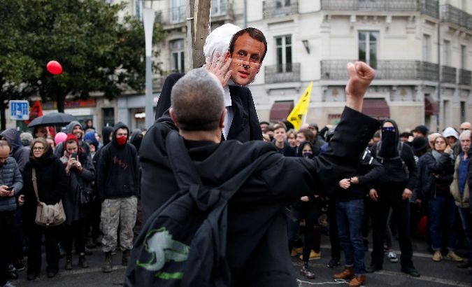 A protester punches a dummy depicting French President Emmanuel Macron in Nantes, France.