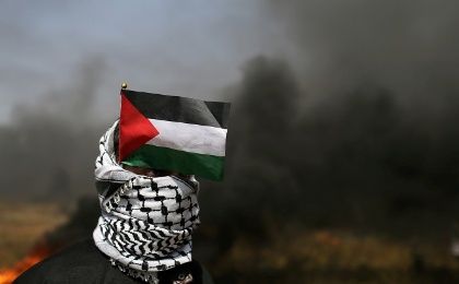 A demonstrator with a Palestinian flag looks on during clashes with Israeli troops at a protest demanding the right to return to their homeland, in the southern Gaza.